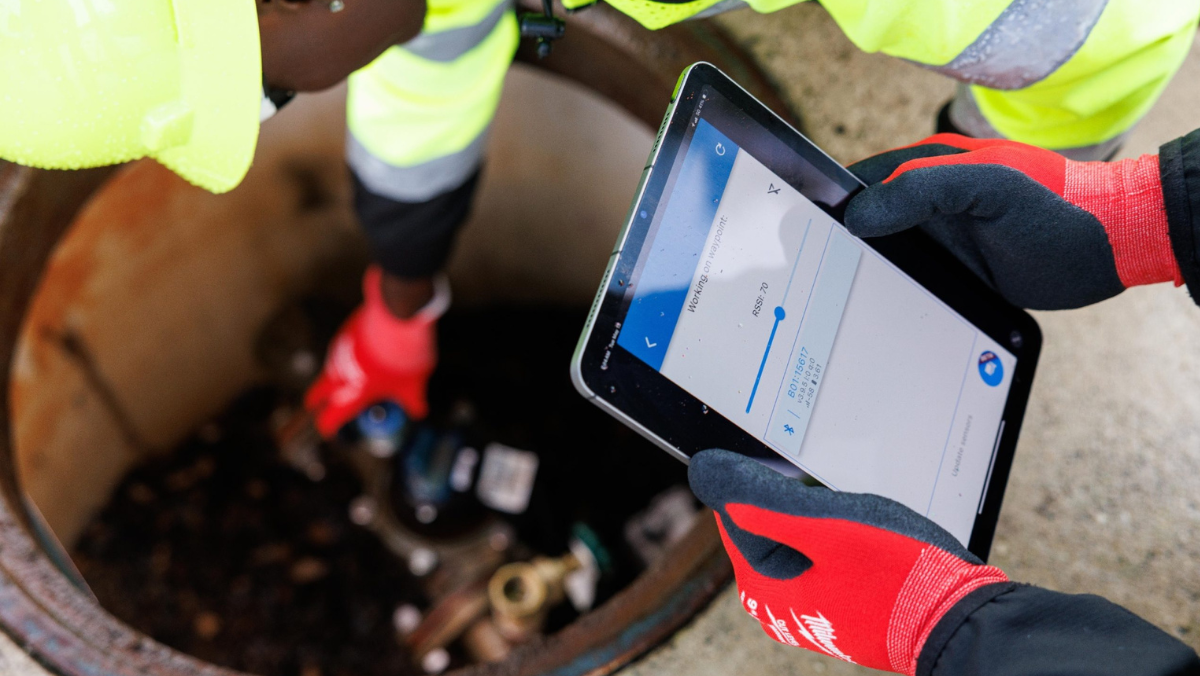 Worker using tablet to inspect underground water system with AI leak detection tools
