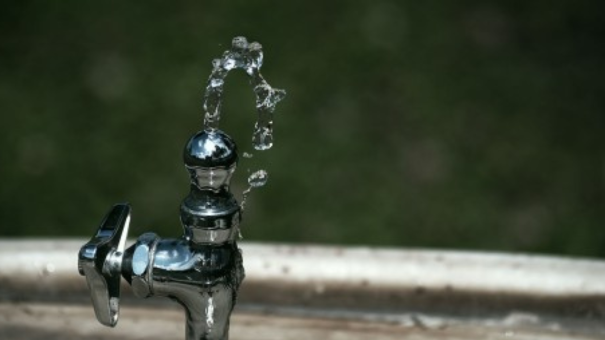 Close-up of a leaking outdoor water tap illustrating pipe aging and water loss issues.